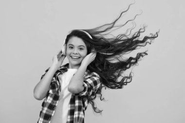 Child music concept. Teenager child girl dances in rhythm of melody, listens song in headphones. Child listening to music through earphones. Happy teenager, positive and smiling emotions of teen girl