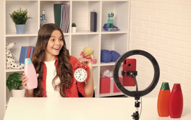 Teen girl blogger influencer use selfie led lamp and smartphone on tripod for making online video tutorial. Teenager vlogger making vlog for kids channel. Happy smiling girl