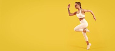 Sarı arka planda spor giyinen fitness kızı. Kopyalama alanı ile çalışan kadın pankartı