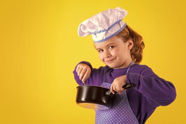 Aşçı çocuk tencereyle yemek pişiriyor. Heyecanlı aşçı şefi. Çocuk fırın üniforması ve aşçı şapkası giyiyor yemek hazırlıyor, stüdyo fotoğrafı çekiyor.