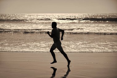silhouette of sporty man runner sprinting on beach outdoor, achievement.