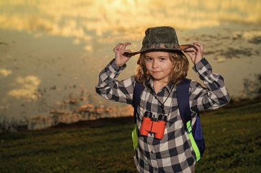 Dürbünlü çocuk dışarıda geziyor. Yaz günü sırt çantalı bir gezgin. Vahşi hayatı keşfeden küçük bir çocuğun portresi. Yürüyüş ve macera konsepti