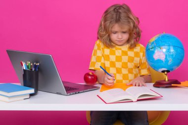 İlkokulda okuyan bir okul çocuğu. Pembe kırmızı izole edilmiş arka plan üzerine ders çalışan çocuk