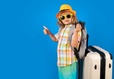 Stüdyo arka planında bavulu olan çocuk gezgin. Turist çocuk. Seyahat çantasıyla çocuk portresi. Seyahat, macera, tatil