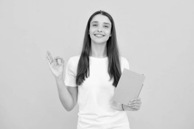 Young student girl in casual clothes, isolated on yellow background studio portrait. Hold notebooks. Cheerful young attractive student woman