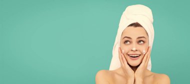 Cilt bakımlı güzel kadın. Genç bayanın mavi arka plana yüz kremi sürmesine şaşırdım. Güzel kadın, izole edilmiş yüz portresi, taklit alanı olan pankart.