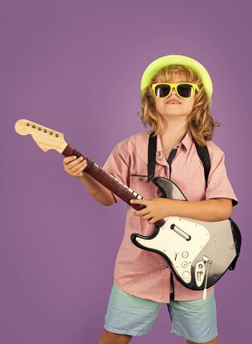 Moda Amerikalı taşra çocuğu müzik çalıyor. Gitar çalışmasındaki sevimli çocuk portresi. Gitarlı komik rock çocuğu