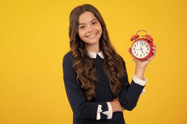 Öğrenci kız saati sarı arka planda izole edilmiş. Okula gitme vakti. Alarmlı saati olan genç bir çocuk, uyanma zamanını gösteriyor.