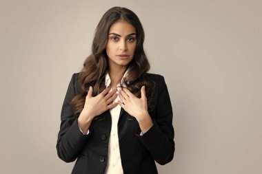 İş kadını portresi. Çekici genç, oldukça neşeli takım elbiseli iş kadını, izole edilmiş gri bir geçmişi var.