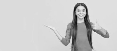 Sarı arka planda fotokopi alanı ve reklamı olan bir ürün sunan mutlu çocuk. Çocuk yüzü, yatay poster, izole edilmiş genç kız portresi, fotokopi alanı olan pankart