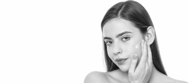 Kadın yüzü, yakın portre, kopyalanmış afiş. Beyaz arka planda izole edilmiş cilt kremi süren genç bir kadın, günlük alışkanlık.