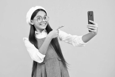 Kids selfie. Teenager child girl holding smartphone. Hipster girl with cell phone. Kid hold mobile phone texting in online social networks