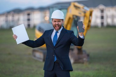 İnşaat mühendisi inşaat alanında çalışıyor. Evin arka planındaki mühendis. Modern ev inşaatında kendine güvenen mühendis. İspanyol inşaat mühendisi miğferinde