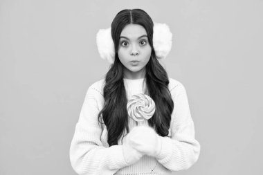 Sarı izole edilmiş arka planda lolipopu olan komik çocuk. Tatlı çocukluk hayatı. Lezzetli karamel lolipopu olan genç kız, şekerci. Şaşırmış genç kız.