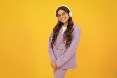 Child listening music with headphones. Girl listening songs via wireless earphones. Headset device accessory. Stylish teenage girl listening to music