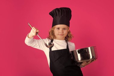 Child chef cook with cooking pot and ladle. Cooking children. Chef kid boy making healthy food. Portrait of little child in chef hat isolated on studio background. Kid chef. Cooking process