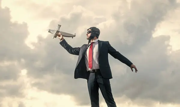 stock image businessman in suit and pilot hat launch plane toy on sky background. boost idea.