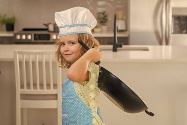 Kid chef cook wearing cooker uniform and chef hat preparing food on kitchen. Cooking, culinary and kids food concept
