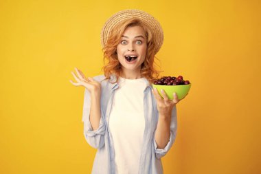 Sarıya izole edilmiş vişne tabağı olan hoş bir kadın.