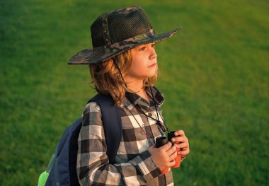 Gezgin şapkalı ve sırt çantalı izci çocuk. Dürbünlü kaşif ve macera
