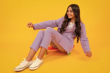 Fashion teenage lifestyle, beautiful teen girl with skateboard isolated on studio background