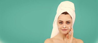 Skin care beauty woman. smiling young girl apply face cream on blue background. Beautiful woman isolated face portrait, banner with mock up copy space