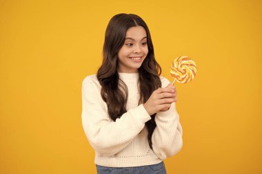 Heyecanlı bir yüz. Şekerli lolipopu olan genç bir kız, 12, 13, 14 yaşlarında şeker yiyip şeker yiyen mutlu bir çocuk. Mutlu yüz, pozitif ve gülümseyen genç kız duyguları