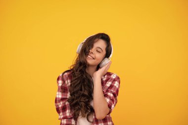 Child listening music with headphones. Girl listening songs via wireless earphones. Headset device accessory. Stylish teenage girl listening to music