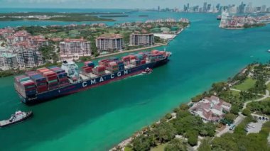 Miami, Florida, ABD - 23 Haziran 2024: Kargo gemisi limana giriyor. Konteyner gemisi. Konteynırlı kargo gemisi, hava manzaralı. Kargo gemisindeki nakliye konteynırı Fisher Adası 'nı geçiyor. Kargo lojistiği.