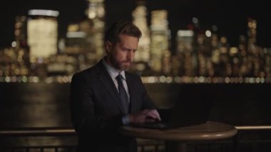 İş adamı dışarıda bilgisayar ya da dizüstü bilgisayarda çalışmakla meşgul. Adam internet tarayıcısından iş e-postası ve sörf yolluyor. New York 'ta serbest çalışan bir iş adamı. İnternette çalışan bir iş adamı. Yakınlaştır.