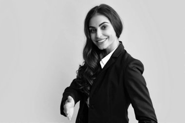 Takım elbiseli bir iş kadını gülümseyerek selamlama ve hoş geldin demek için tokalaşıyor. İş kadını tokalaşıyor. Selamlama ve hoş geldin olarak el sıkışmayı teklif ediyorum. Kadın çalışan sekreteri