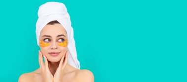 smiling young lady has collagen golden eye patches on face with towel. Beautiful woman isolated face portrait, banner with mock up copy space clipart