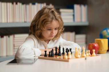 Erken gelişen çocuklar. Çocuk evde satranç oynuyor. Konsantre çocuk satranç stratejisi geliştiriyor, masa oyunu oynuyor