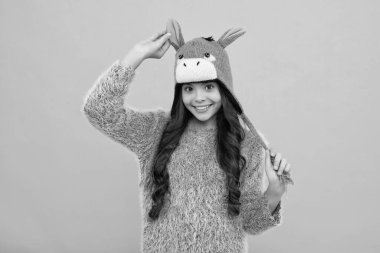 Modern teenage girl 12, 13, 14 year old wearing sweater and knitted hat on isolated yellow background. Happy face, positive and smiling emotions of teenager girl