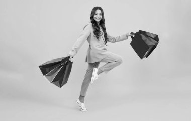 Alışveriş torbaları olan şık bir genç kız. Koş ve atla. Alım satım yapan çocuklar