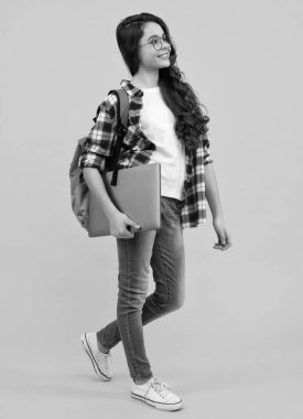 Dizüstü bilgisayarlı okul üniformalı kız. Öğrenci, sarı izole edilmiş bir geçmişi olan genç bir öğrenci. Mutlu ergen, pozitif ve gülümseyen genç kız duyguları