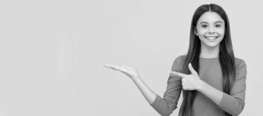 Mutlu çocuk, uzun saçlı, ürününü sunan ve fotokopi alanı ve reklamında parmağıyla işaret eden. Çocuk yüzü, yatay poster, izole edilmiş genç kız portresi, fotokopi alanı olan pankart