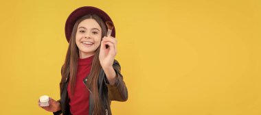 happy child in hat apply powder on yellow background, beauty. Cosmetics for teenager child, poster design. Beauty kids makeup, banner with copy space