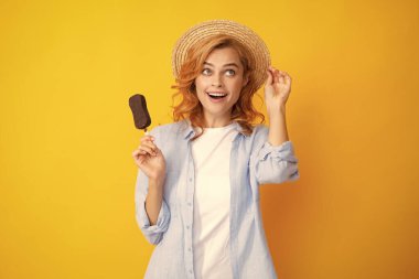 Sarı arka planda çikolatalı dondurmalı kızıl saçlı kızın portresi. Dondurma yiyen kıvırcık, neşeli kadın.