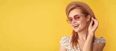 Woman isolated face portrait, cheerful young woman in straw hat and sunglasses on yellow background. Woman isolated face portrait, banner with mock up copy space