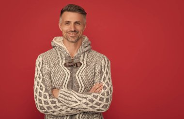 Kırmızı arka planda süveter giyen gülümseyen adam fotokopi alanı, moda.