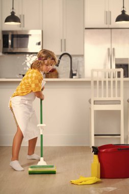 Child do chores cleaning floor. Little kid cleaning at home. Child doing housework having fun. Portrait of child housekeeper with wet flat mop on kitchen interior background