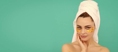 Eye patches, patch under eyes. young woman has collagen golden eye patches on face smile with towel. Beautiful woman isolated face portrait, banner with mock up copy space