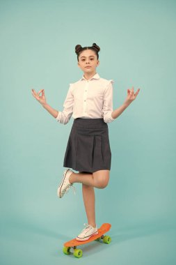 Teen girl 12, 13, 14 years old with skateboard over studio background. Cool modern teenager in stylish clothes. Teenagers lifestyle, casual youth culture