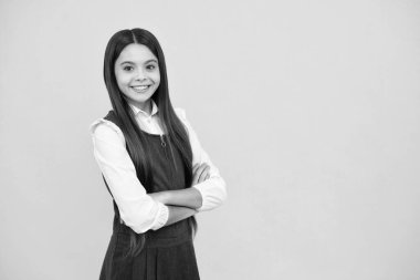 Happy girl face, positive and smiling emotions. Portrait of teenager girl crossed arms isolated on yellow background. Children lifestyle childhood concept