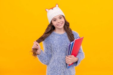 Süveterli ve şapkalı mutlu çocuk sarı arka plan çalışma kitabı, ev ödevi.