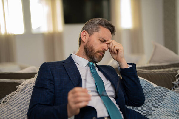 У уставшего человека ужасная головная боль. Уставший человек чувствует себя нездоровым, расстроенным из-за головной боли. У мужчины средних лет стресс от головной боли. Концепция мигрени и головной боли