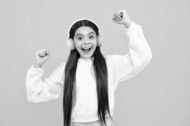 Heyecanlı bir yüz. Çocuk müziği konsepti. Genç kız melodiyle dans ediyor, kulaklıkla şarkı dinliyor. Çocuk kulaklıkla müzik dinliyor. Şaşırtıcı bir ifade, neşeli ve mutlu.