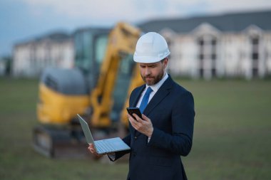 İnşaat mühendisi inşaat alanında çalışıyor. Evin arka planındaki mühendis. Modern ev inşaatında kendine güvenen mühendis. İspanyol inşaat mühendisi miğferinde