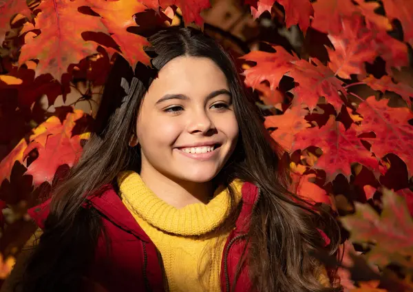 Mutlu çocuk güzel sonbahar yapraklarında duruyor..